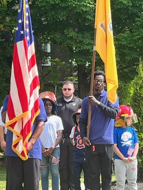 Flags of NJ and USA held by vets with 3 children standing behind them