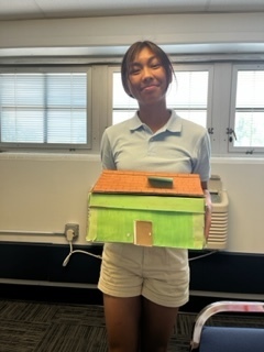 Student holding box in shape of a house